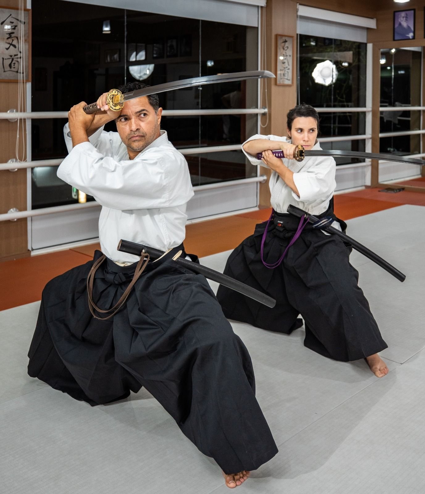 Sensei Francisco Santiago e Sensei Bárbara Belafronte em postura de iai-dō, de hakama, com as espadas erguidas
