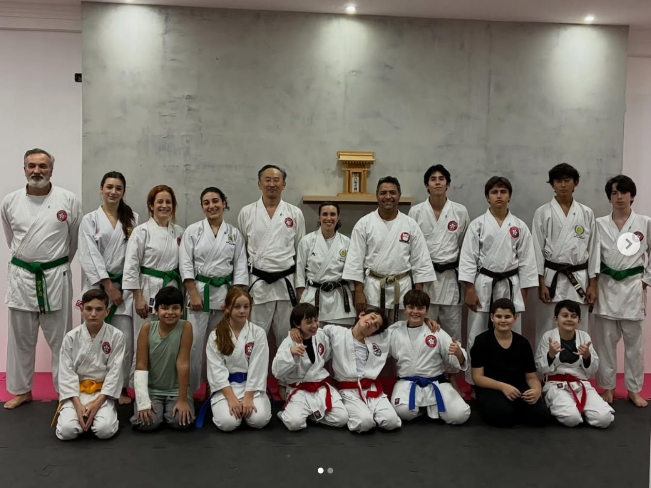 Turma da Renbukan reunida no dojo, adultos em pé e crianças sentadas
